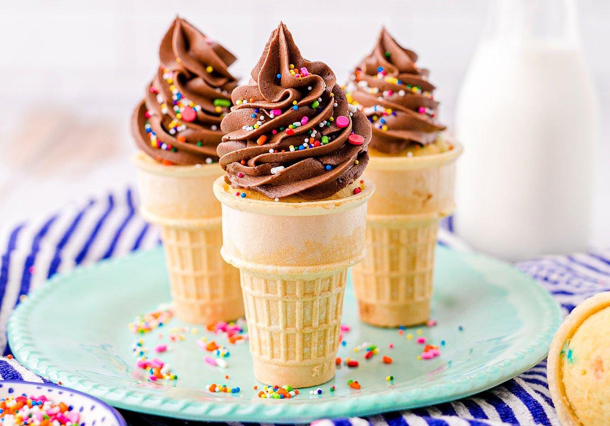 Κεκάκια Χωνάκι Παγωτού 2 Τρία cupcakes σε χωνάκι παγωτού με σοκολατένια βουτυρόκρεμα και πολύχρωμη τρούφα βρίσκονται σε ένα πράσινο πιάτο δίπλα σε ένα μπουκάλι γάλα – τέλεια cupcakes για πάρτι γενεθλίων.