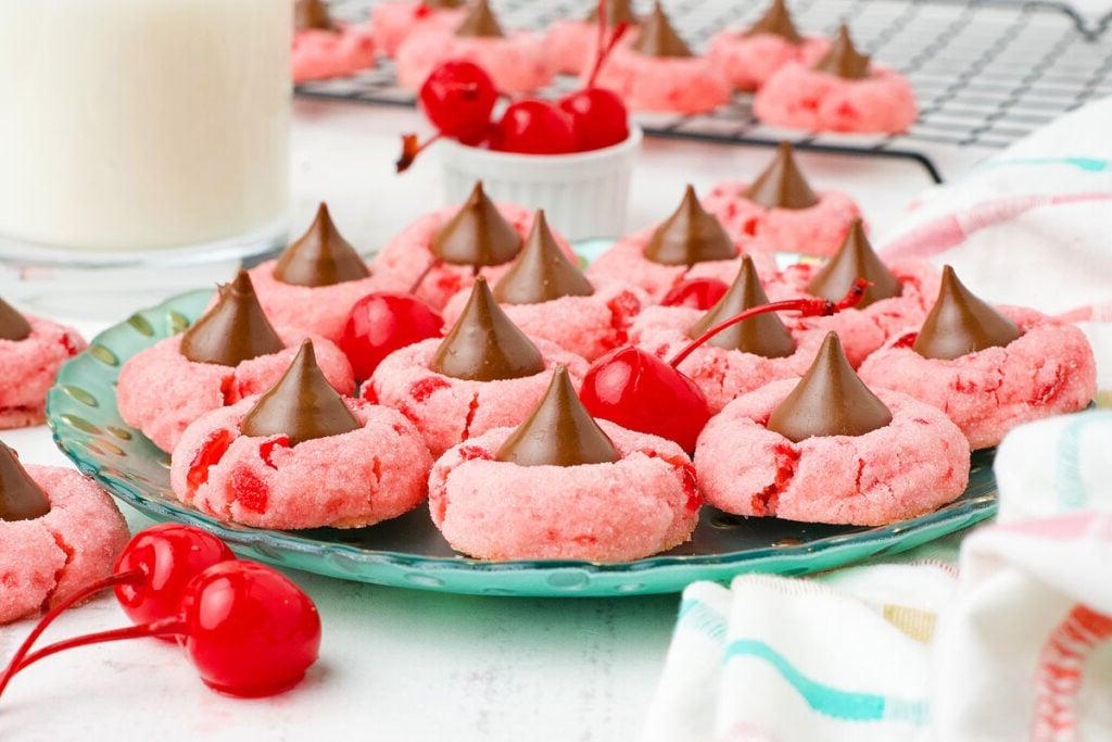 21 Λαχταριστές Συνταγές με σοκολάτα Hershey's Kiss 2 Ροζ μπισκότα σοκολάτας με κεράσι σε ένα πράσινο πιάτο, το καθένα με ένα σοκολατάκι Hershey's στην κορυφή.