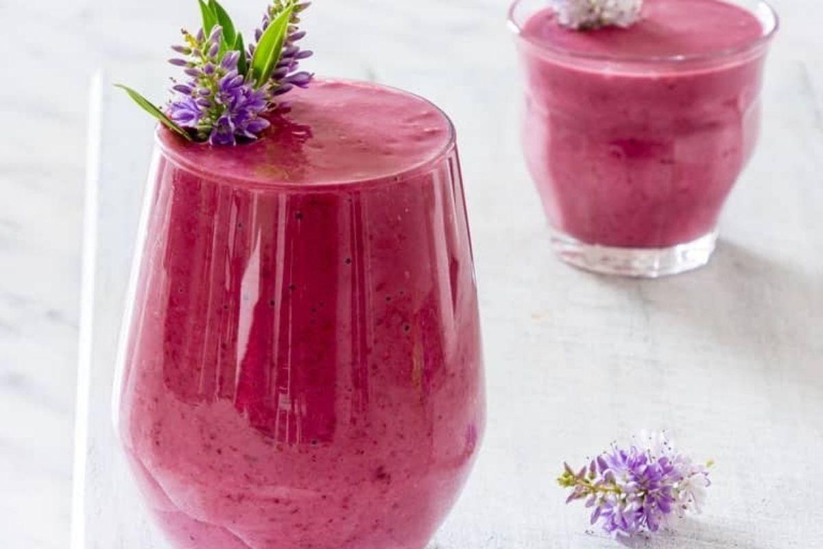 27 Εύκολες Συνταγές Smoothie για να Κάνουν την Ημέρα σας Καλύτερη 15 Ένα μωβ smoothie με λουλούδια λεβάντας pinwheel από πάνω.