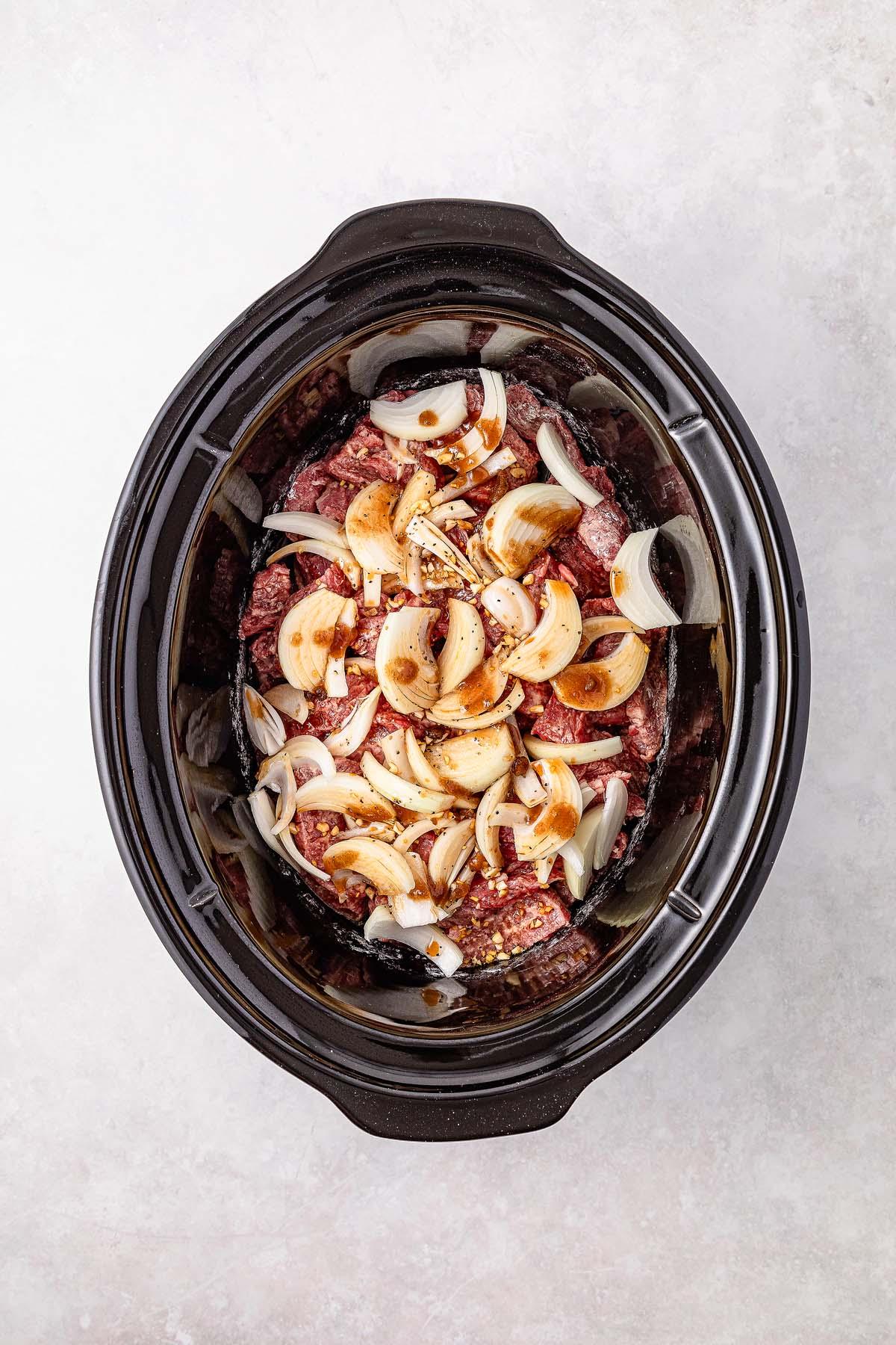 **Σιγομαγειρεμένο Μογγολικό Βοδινό** 16 Savor the simplicity of slow cooker Mongolian beef with raw beef slices, chopped onions, and spices gently mingling on a pristine white surface.