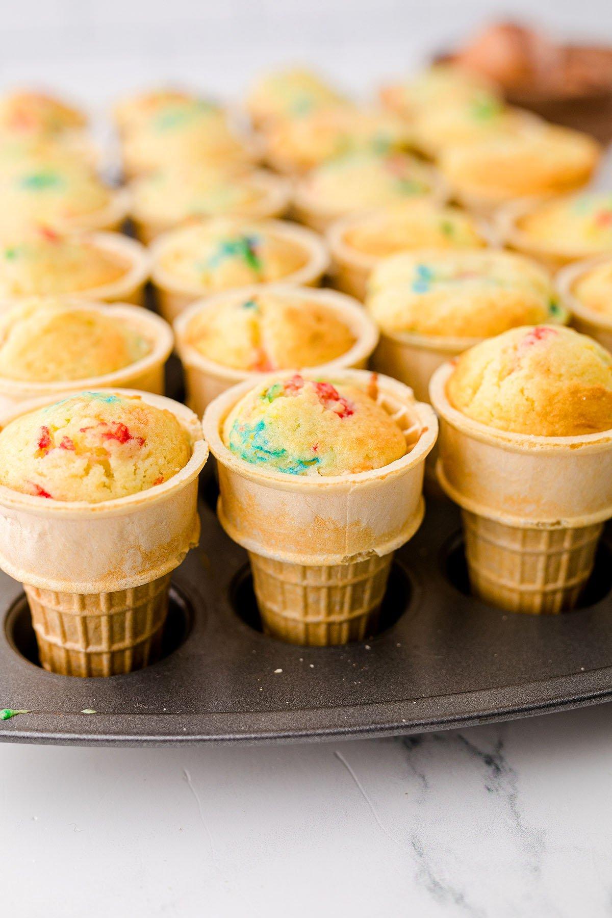 Κεκάκια Χωνάκι Παγωτού 17 Cupcakes σε χωνάκι παγωτού με funfetti ψημένο σε σπιτικά χωνάκια κέικ, τοποθετημένα σε μια φόρμα για muffins σε έναν μαρμάρινο πάγκο – τέλεια cupcakes για πάρτι γενεθλίων!