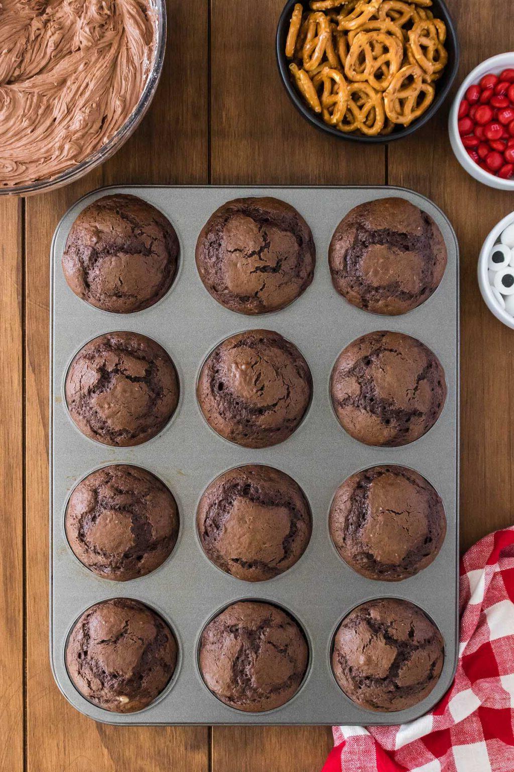 Εύκολα Καπκέικ Ταράνδου 22 Σοκολατένια cupcakes σε φόρμα για muffins με μπαστούνια πρέτσελ, διακοσμημένα σαν τάρανδος.