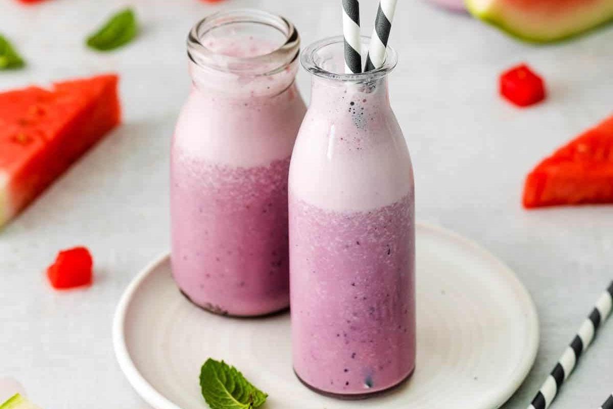 27 Εύκολες Συνταγές Smoothie για να Κάνουν την Ημέρα σας Καλύτερη 26 Δύο μπουκάλια smoothie καρπουζιού σε πιάτο, συνοδευόμενα από συνταγές pinwheel.