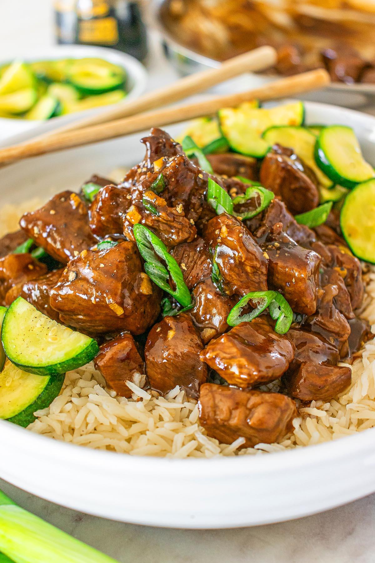 Τεριγιάκι Στέικ Μπουκίτσες 10 Ένα πιάτο stir-fry τεριγιάκι μοσχαριού με κολοκυθάκια σε φέτες και φρέσκα κρεμμυδάκια σερβιρισμένο πάνω σε ρύζι. Τσόπστικς ακουμπούν στην άκρη του πιάτου.