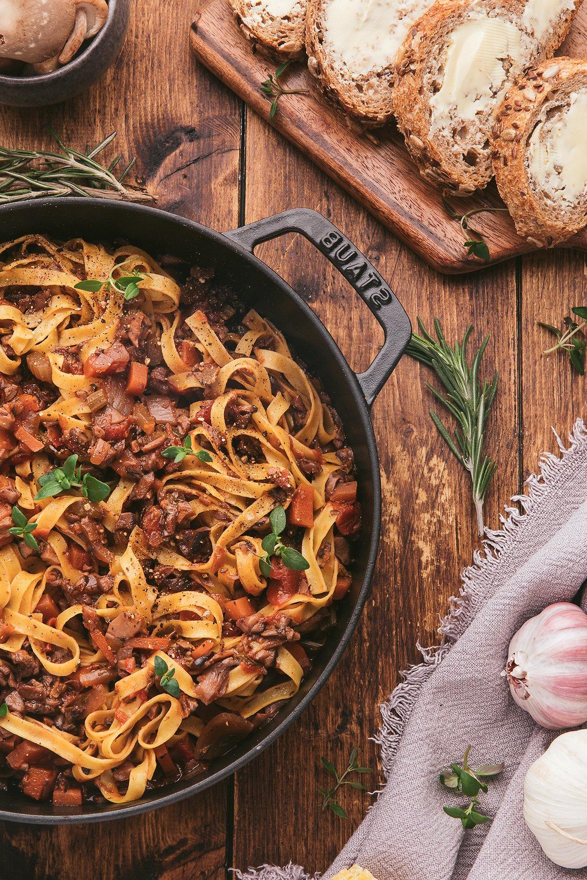 Ραγκού Μανιταριών 10 Τα tagliatelle ζυμαρικά με σπιτική σάλτσα σπαγγέτι με μανιτάρια, σερβιρισμένα σε ένα τηγάνι μαζί με ψιλοκομμένο ψωμί, σκόρδο και φρέσκα βότανα πάνω σε ένα ξύλινο τραπέζι.