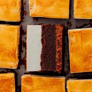 Αρκετά τετράγωνα s'mores brownies με χρυσαφένια επάνω στρώση, διατεταγμένα κοντά το ένα στο άλλο. Ένα μπράουνι στο κέντρο είναι γυρισμένο πλαγίως για να δείξει τις στρώσεις του.