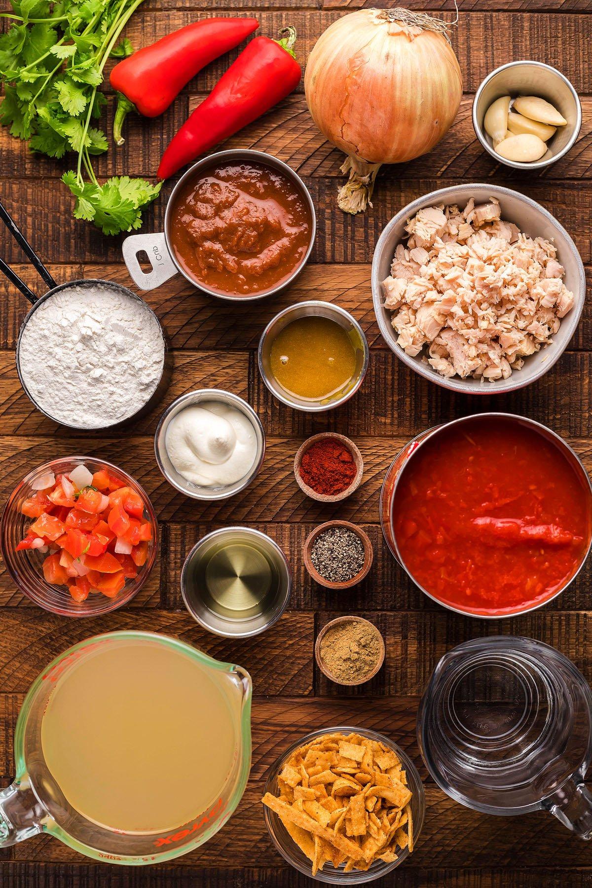Σούπα Εντσιλάδα Κοτόπουλου – Τύπου Chili's 12 Ένα μεξικάνικο μείγμα περιμένει σε μια ξύλινη επιφάνεια, με κοτόπουλο σε κύβους, κρεμμύδι, κόκκινες πιπεριές, ντομάτα, μπαχαρικά και ζωμό. Ιδανικό για μια εύκολη συνταγή σούπας γαρνιρισμένη με λωρίδες τορτίγιας και ξινή κρέμα – ακριβώς όπως ένα αγαπημένο πιάτο Chili's Copycat.