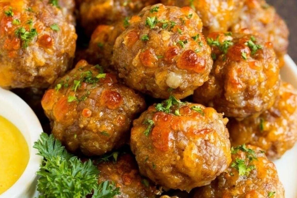 29 Καταπληκτικές Ιδέες Συνταγών με Μίγμα Bisquick 14 Κεφτεδάκια σε λευκή πιατέλα με σάλτσα ντιπ συνταγών Bisquick.