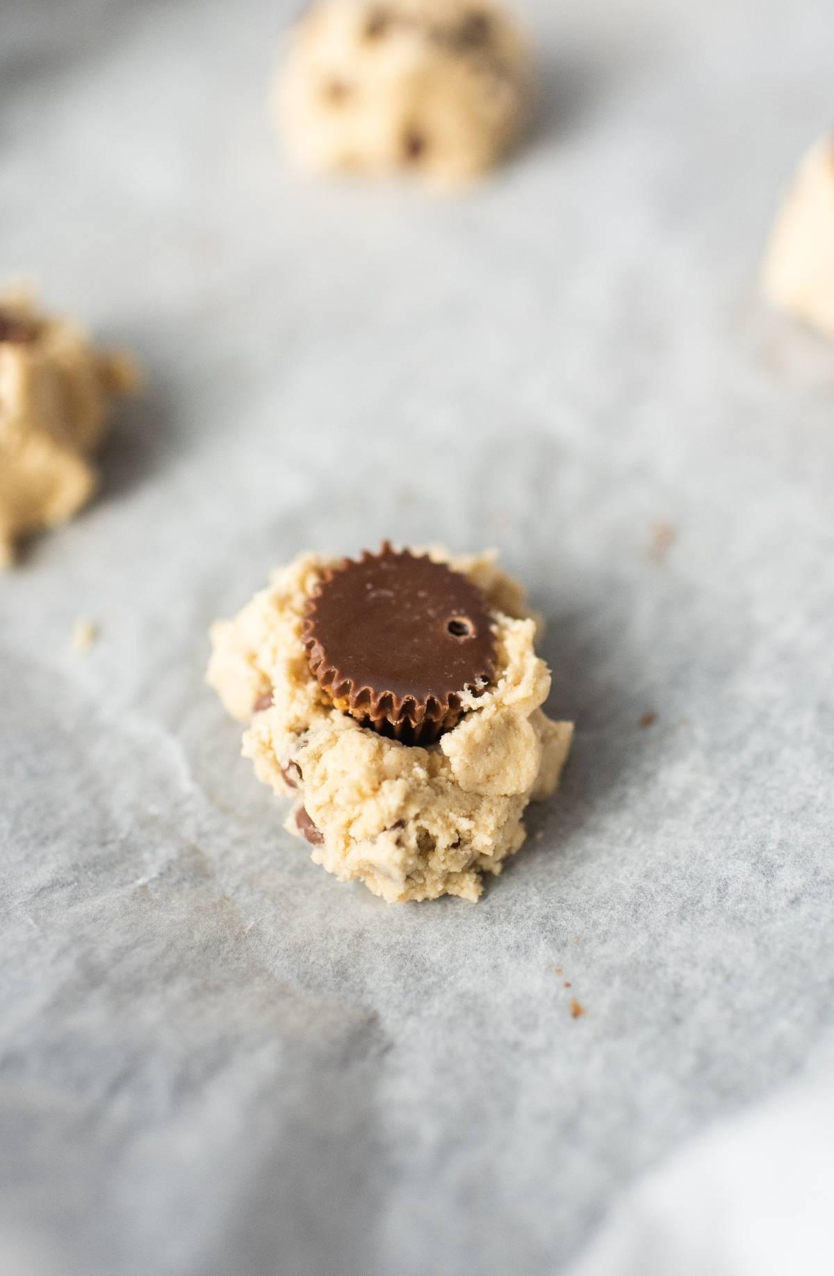 Ζύμη μπισκότων με ένα Reese’s στη μέση σε ένα φύλλο αντικολλητικού χαρτιού, αυτά τα μπισκότα γεμιστά με βούτυρο φιστικιού είναι η απόλυτη λιχουδιά για τους λάτρεις της σοκολάτας.