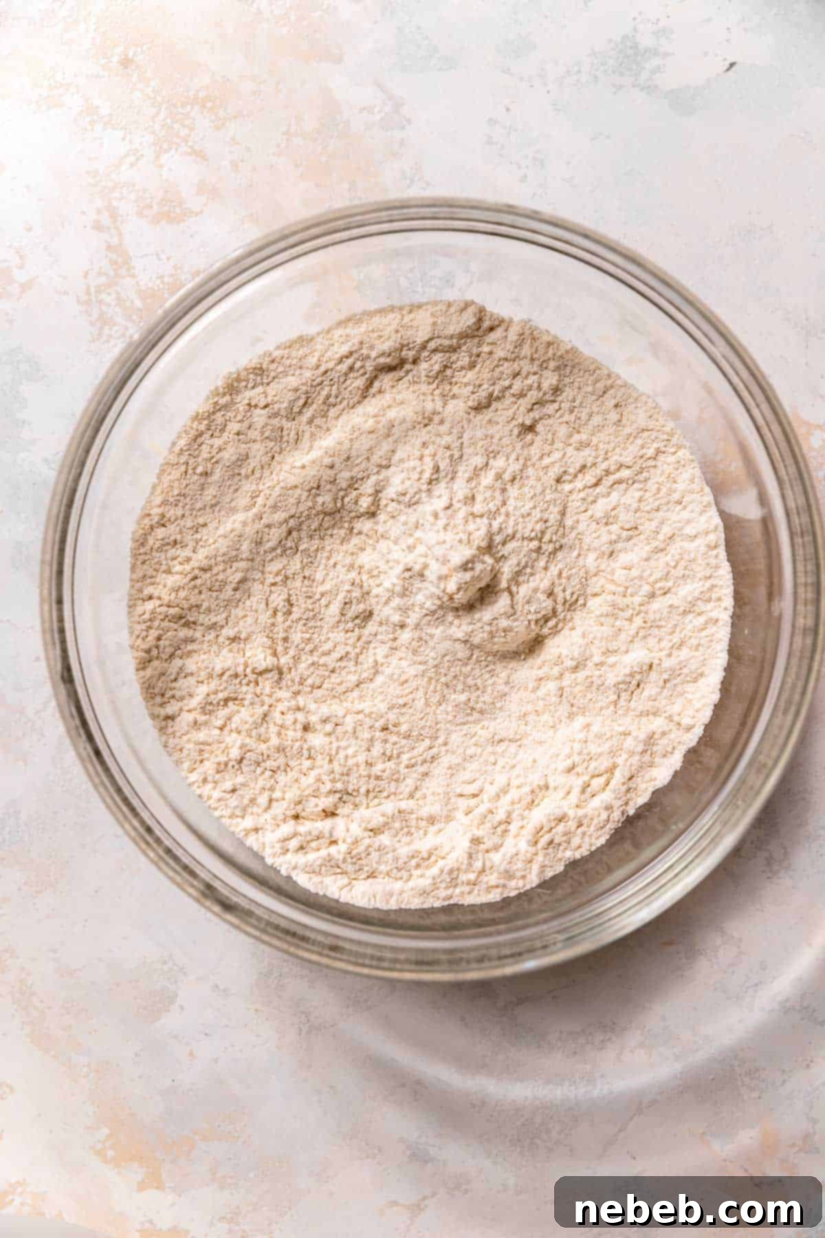 A glass bowl with the whisked dry ingredients for lemon raspberry muffins.