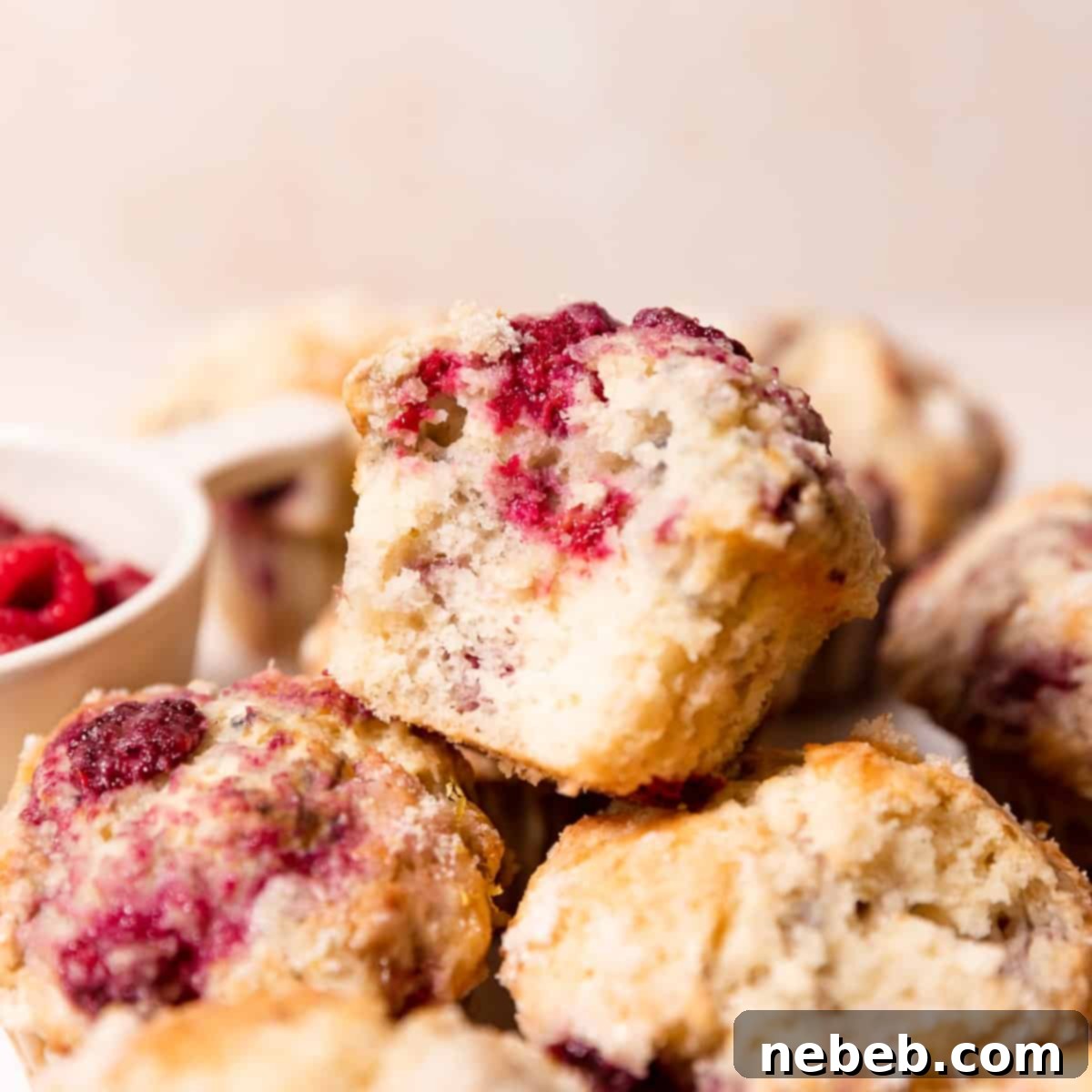 a lemon raspberry muffin with a bite taken out of it, showcasing its moist texture and vibrant berries.