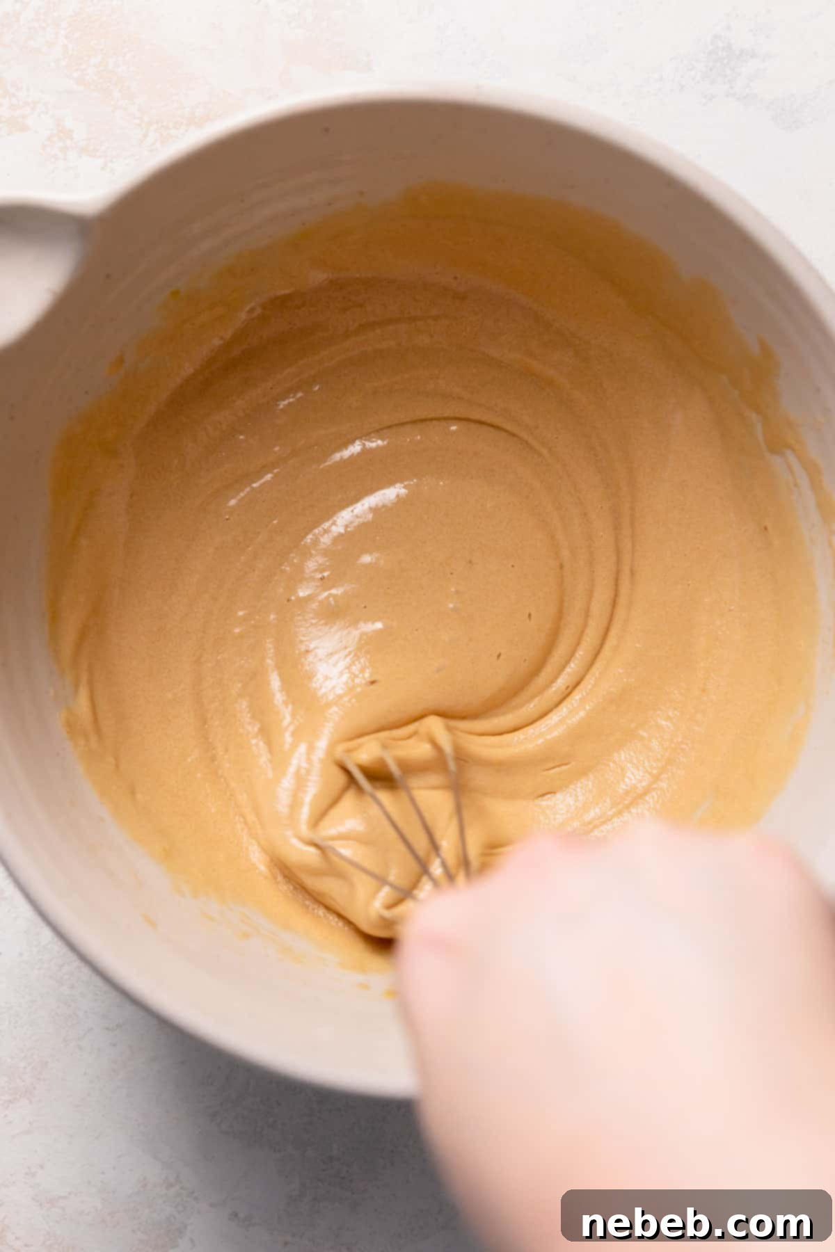 a whisk mixing light brown sugar, granulated sugar, eggs, and vanilla extract in a large mixing bowl.