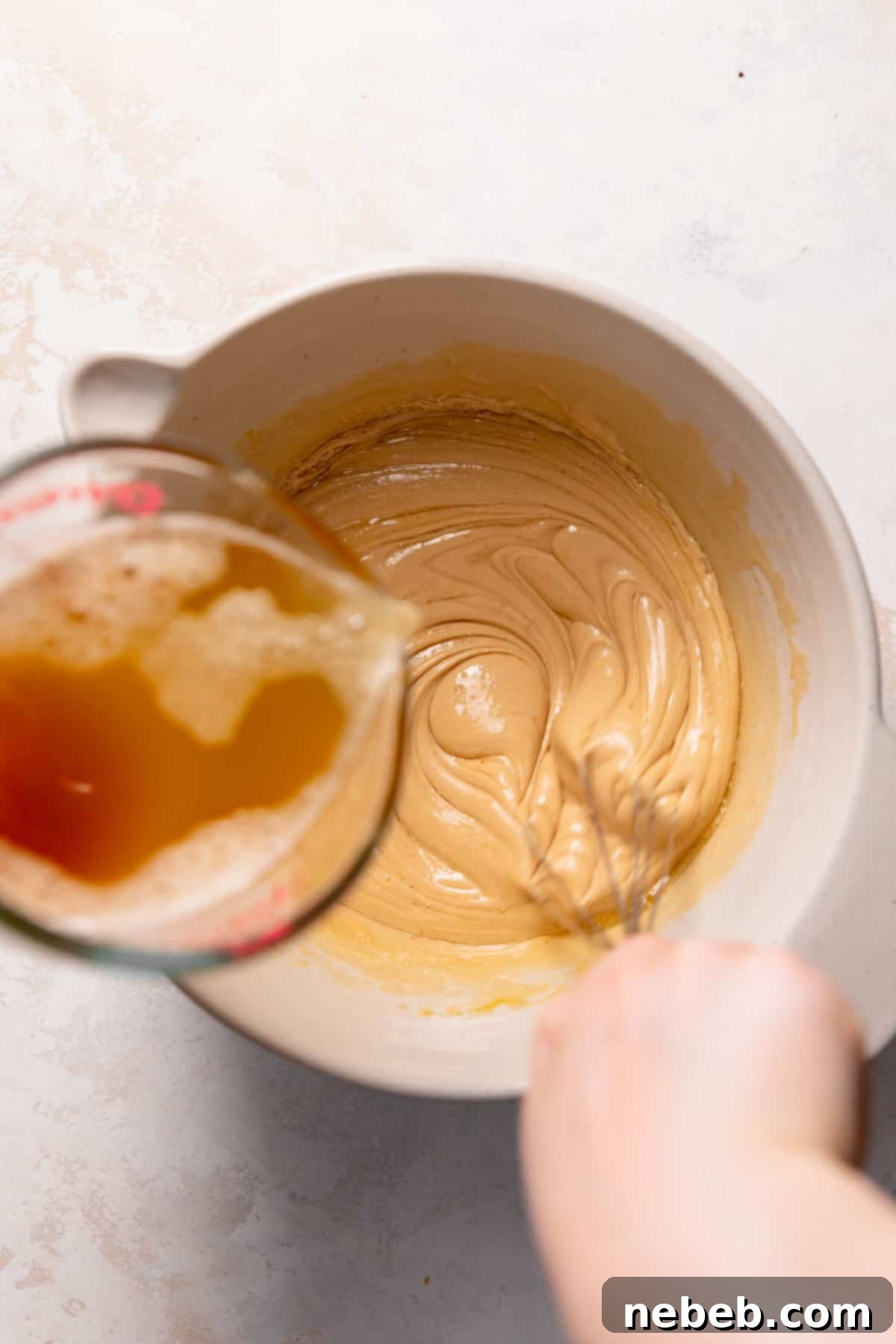 slowly streaming the cooled brown butter into the whisked wet ingredients in a bowl.