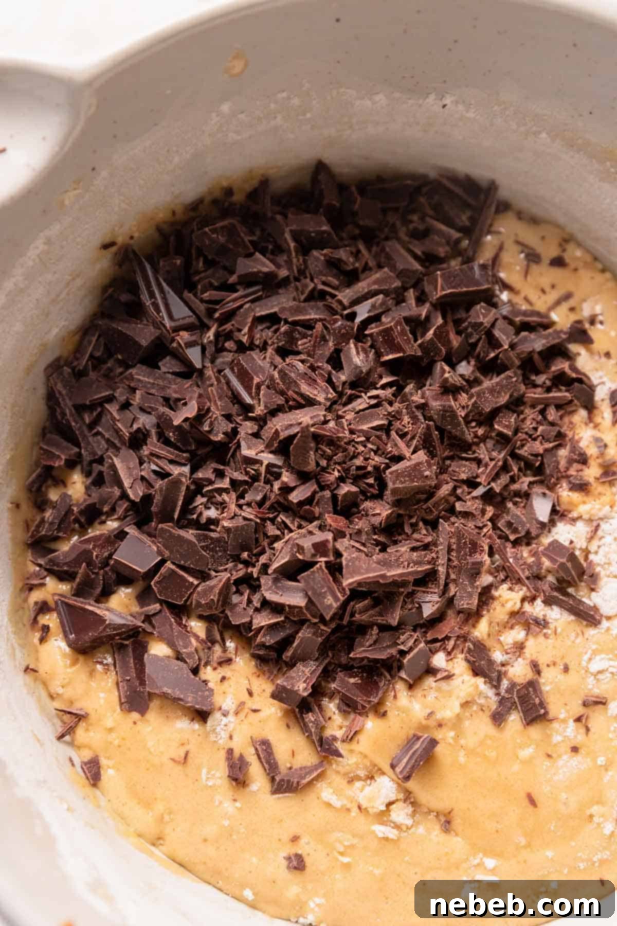 chocolate chips resting on top of the blondie batter in a mixing bowl before folding.
