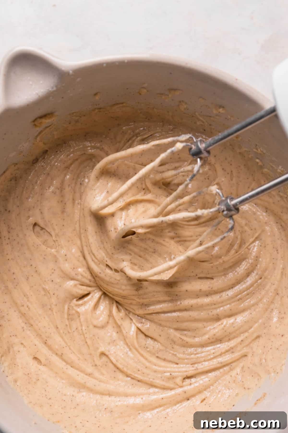 A thick, rich chocolate cake batter paste in a mixing bowl after the first wet ingredients, sour cream and oil, have been added and fully incorporated.