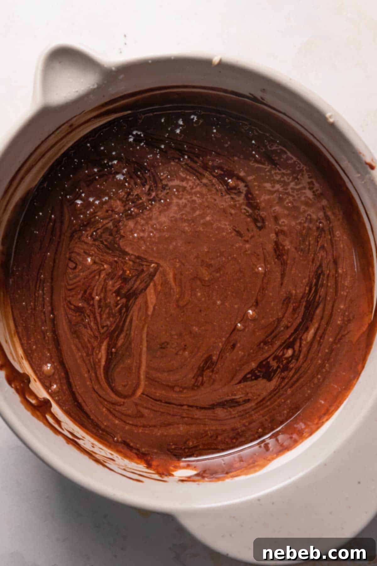 Smooth, glossy chocolate cake batter in a mixing bowl after all wet ingredients, including the hot coffee mixture, are fully incorporated and ready for baking.