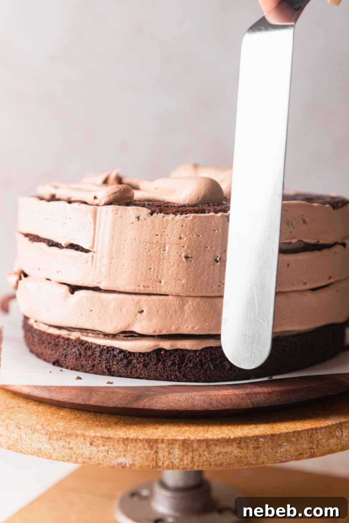 A multi-layered chocolate coffee cake being frosted with smooth, rich coffee buttercream between each layer, ensuring an even distribution of flavor and moisture.