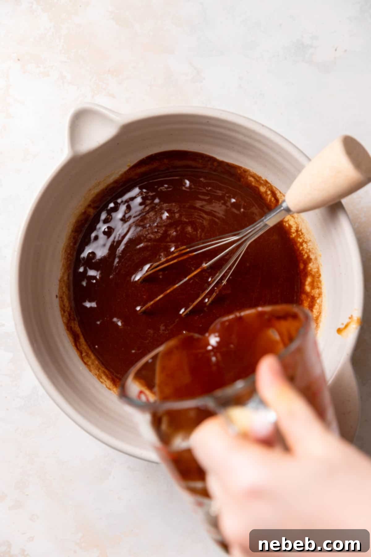 whisking chocolate into the bowl of brownie batter.