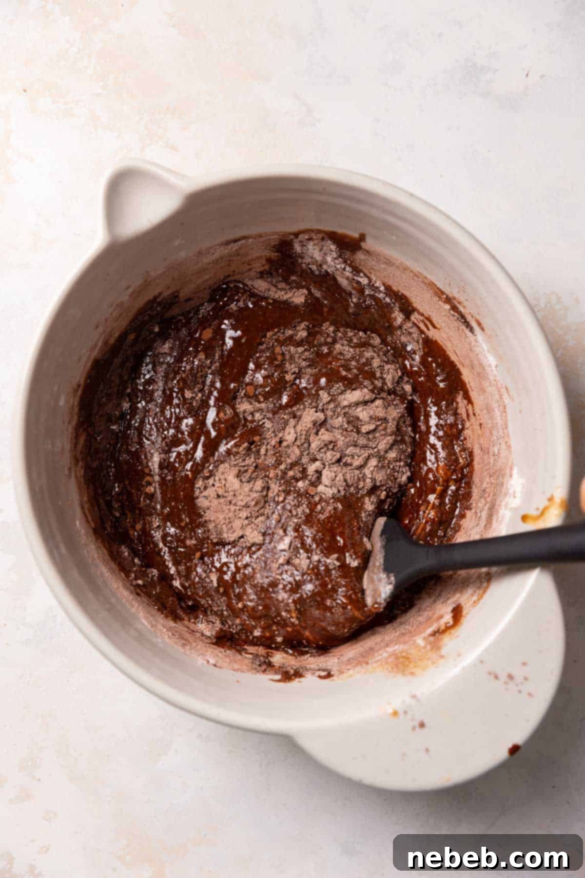 a spatula folding the dry ingredients into the batter.