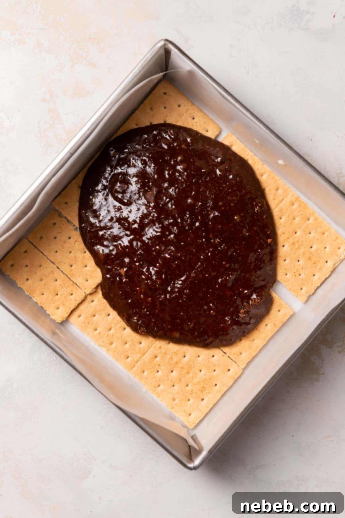 brownie batter being spread across the graham cracker layer.