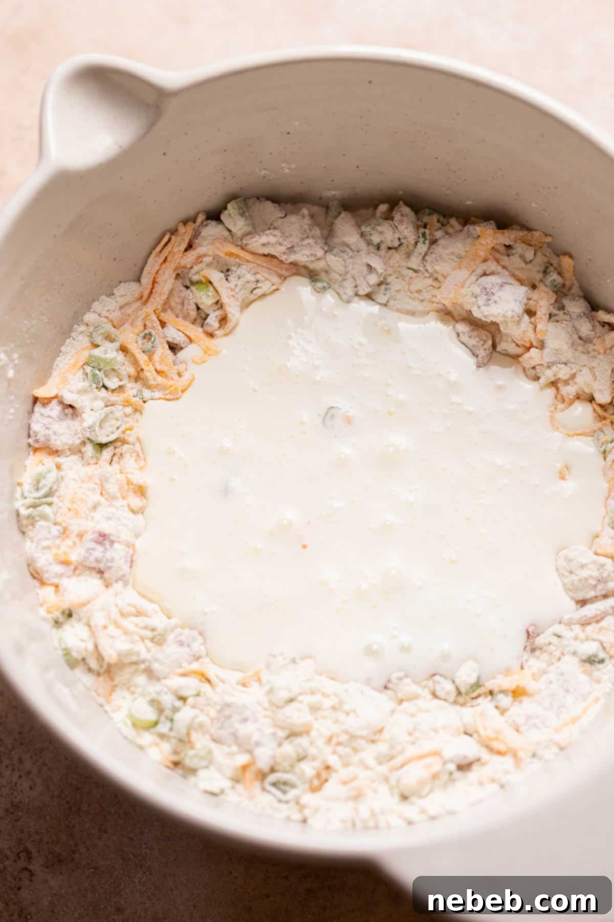 A mixing bowl with the cream poured into the center of the dry ingredients.