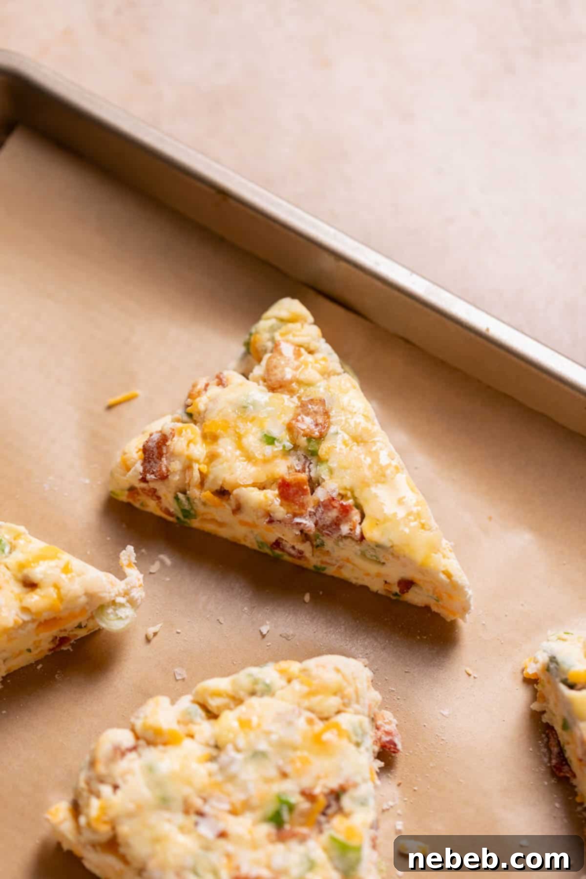 Bacon cheddar scones on a baking tray brushed with egg wash before baking.