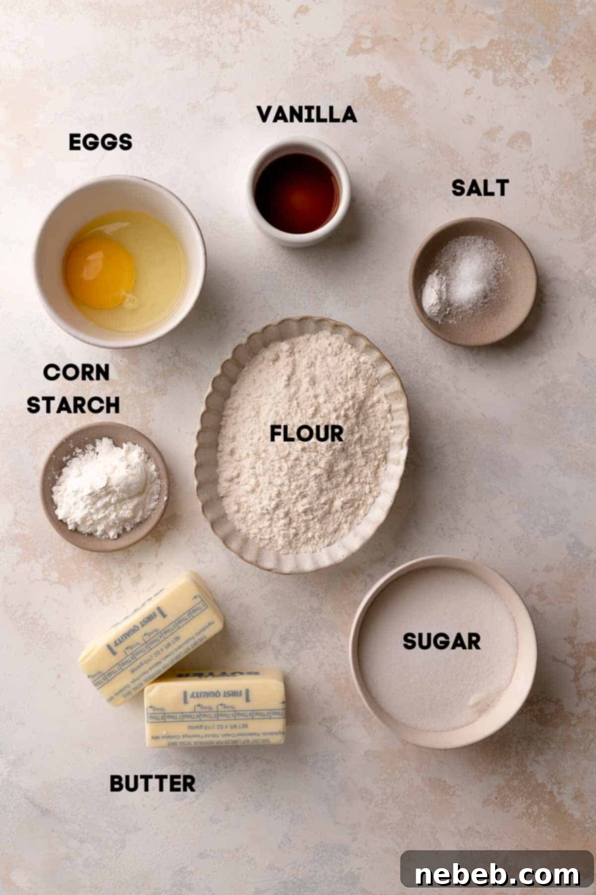 Bowls of pre-measured ingredients like flour, cornstarch, butter, sugar, vanilla extract, and an egg, ready for making shortbread cookie dough.