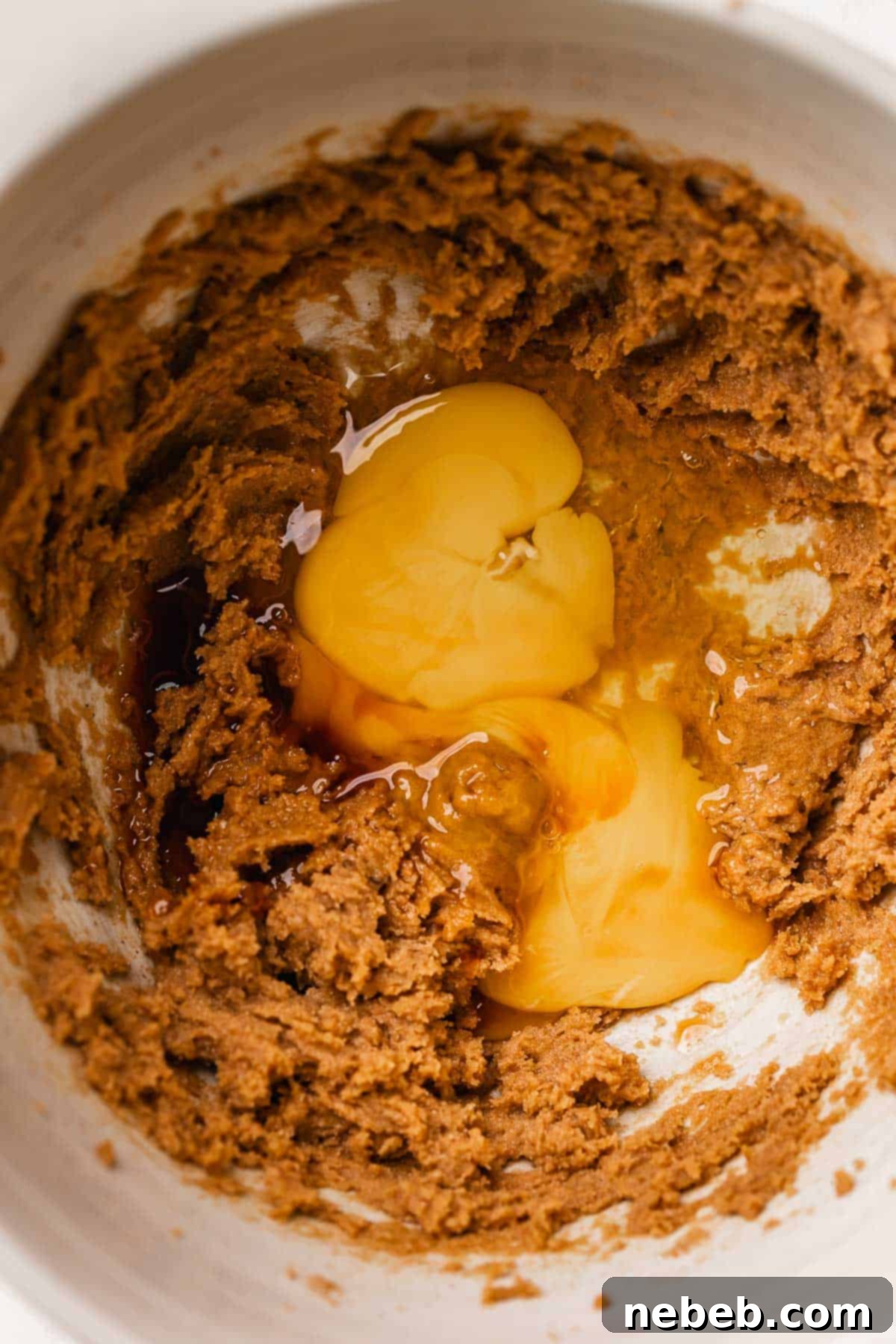 Creamed butter and sugar mixture with egg, egg yolk, and vanilla extract added on top, before mixing.