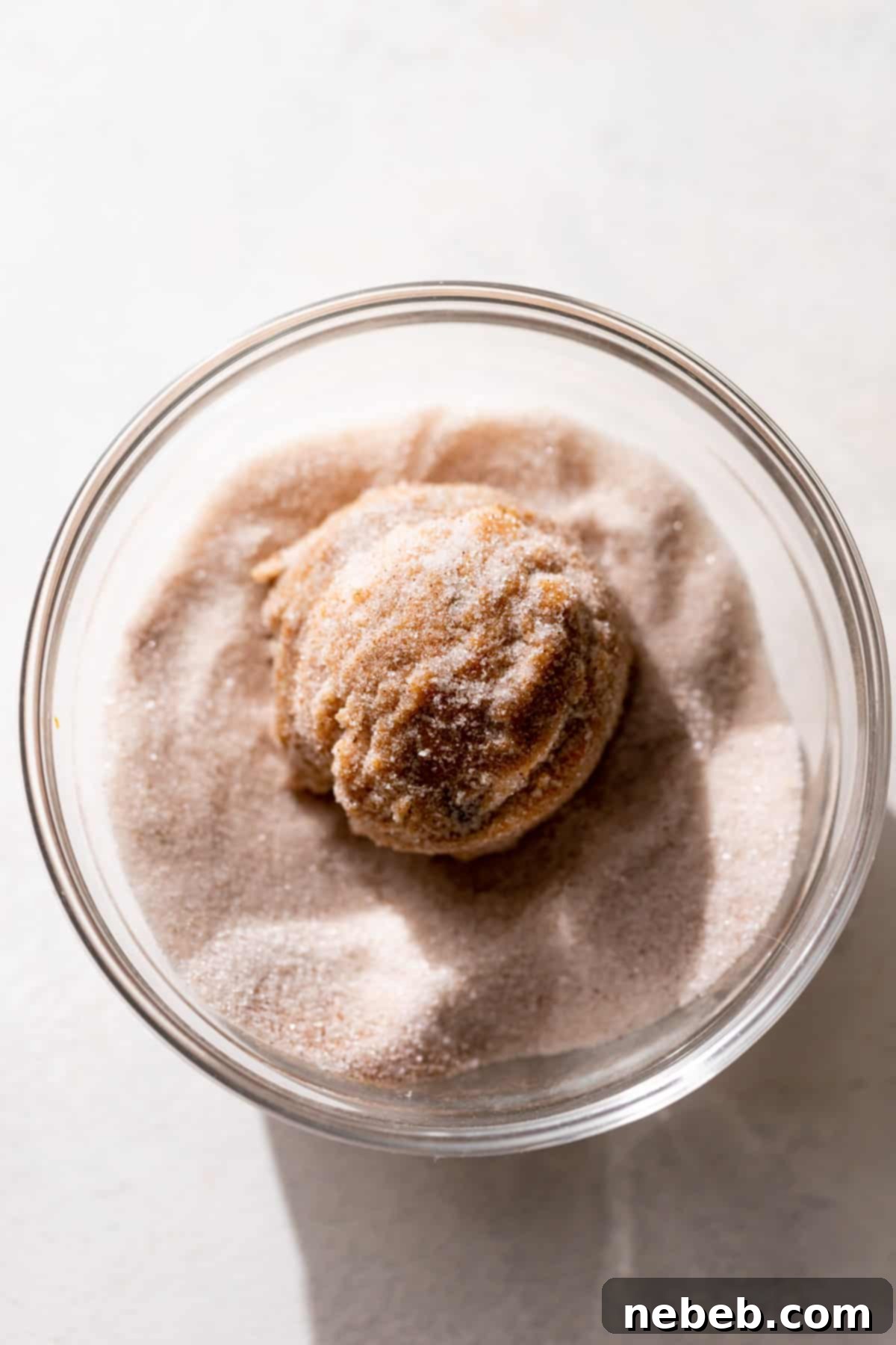 Spiced Pumpkin Snickerdoodle Delights 10 A pumpkin cookie dough ball in a bowl of cinnamon sugar.