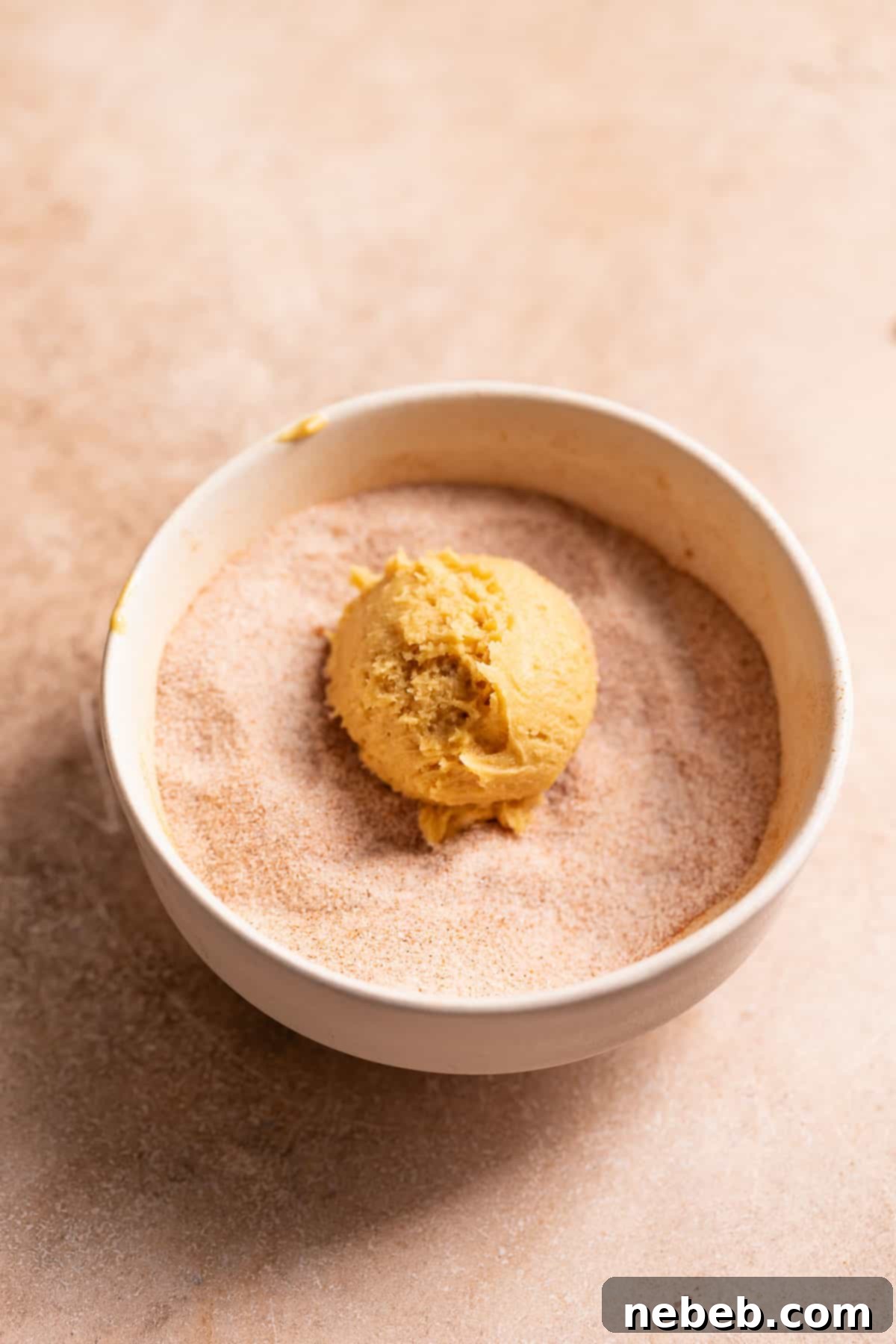 Irresistible Apple Butter Snickerdoodles 6 A snickerdoodle cookie dough ball in a ball of cinnamon sugar.