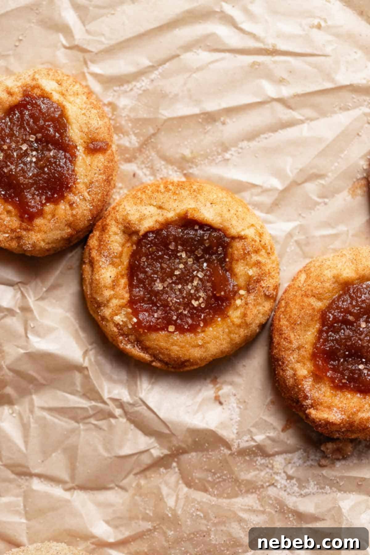 Irresistible Apple Butter Snickerdoodles 9 Snickerdoodle cookies filled with apple butter on brown parchment paper.
