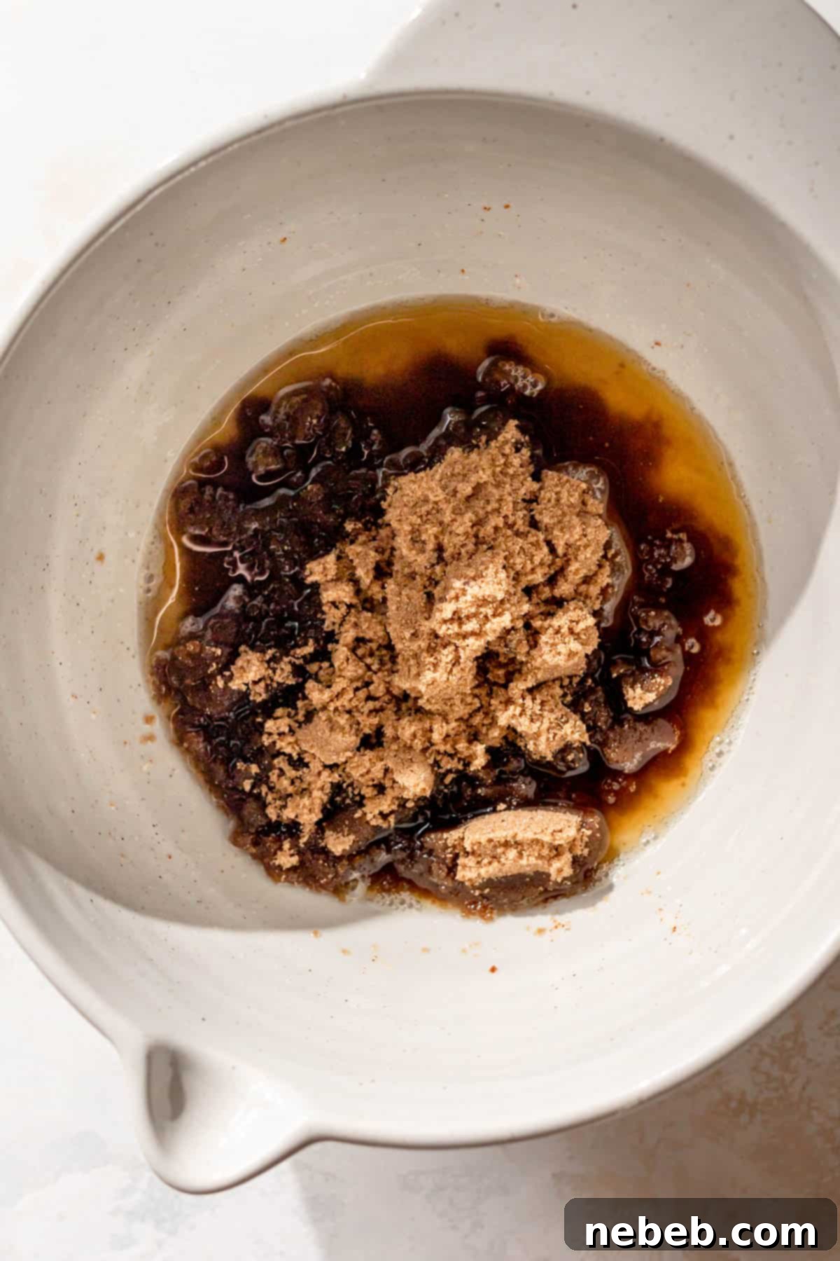 a large bowl with oil, brown butter, and sugar before mixing, showing the distinct layers.