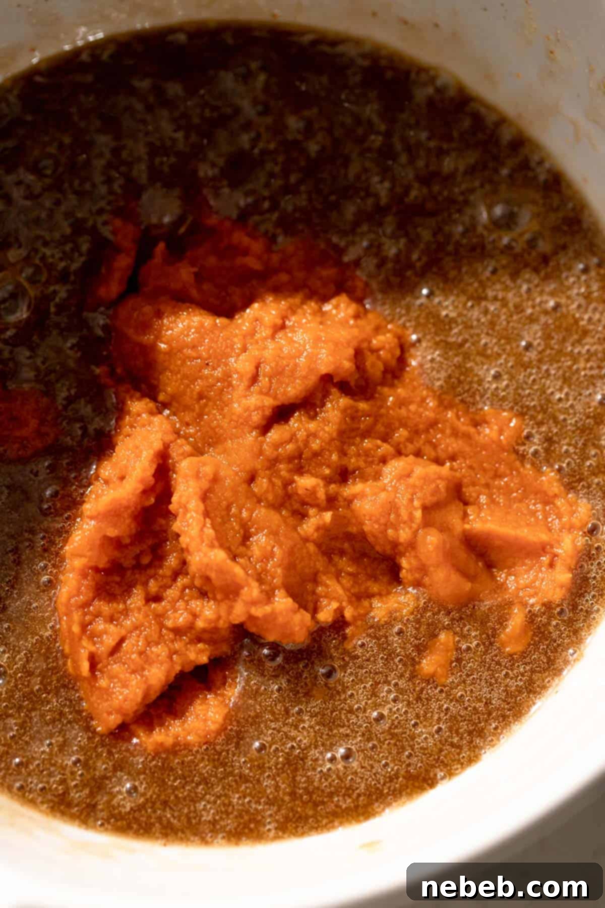 pumpkin puree on top of the wet batter in a mixing bowl, ready to be combined.
