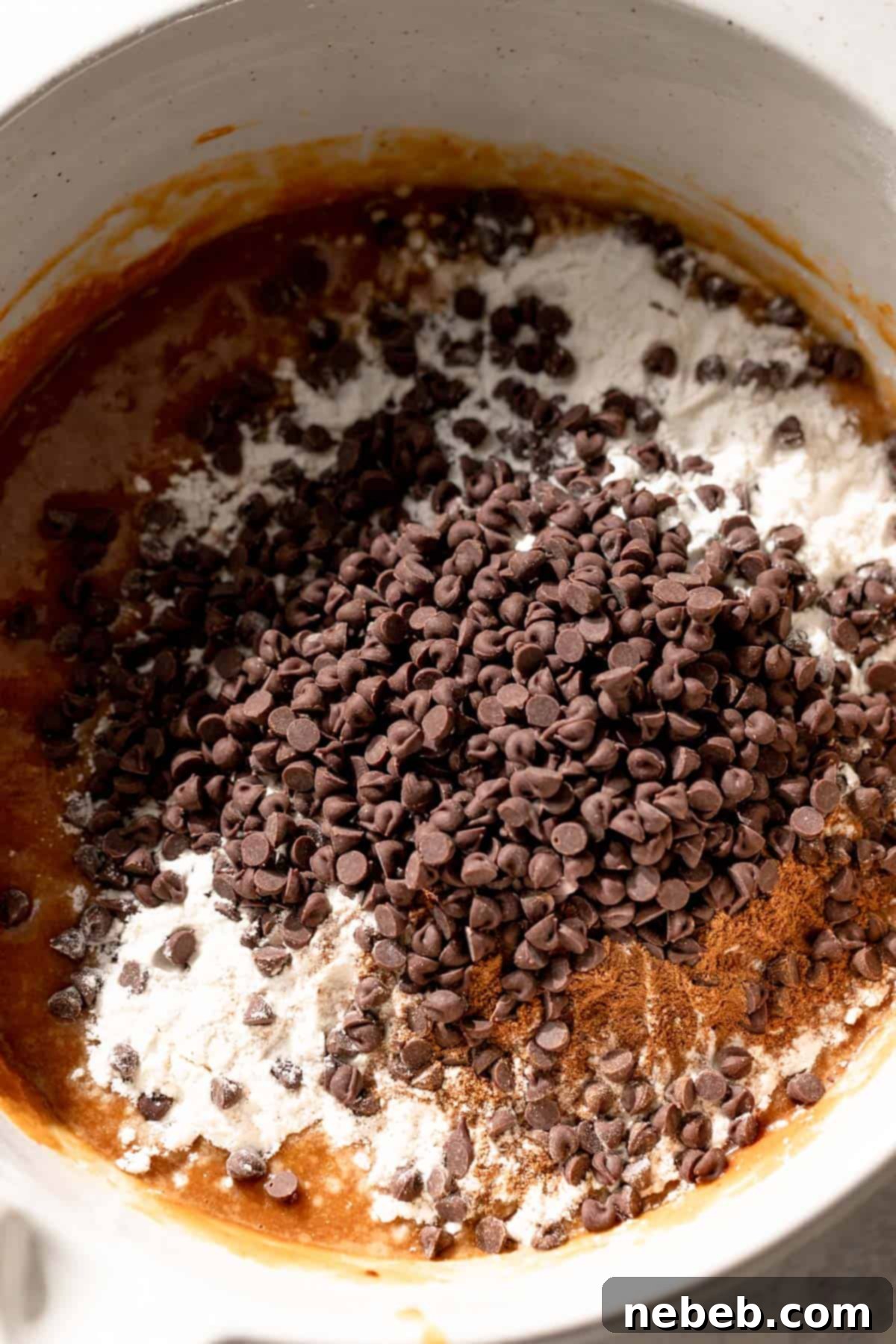 dry ingredients and chocolate chips on top of the pumpkin batter before mixing, showcasing the texture.