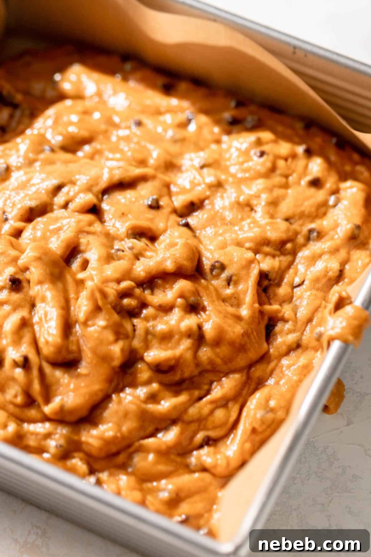 chocolate chip pumpkin cake batter in a baking pan, topped with extra mini chocolate chips.
