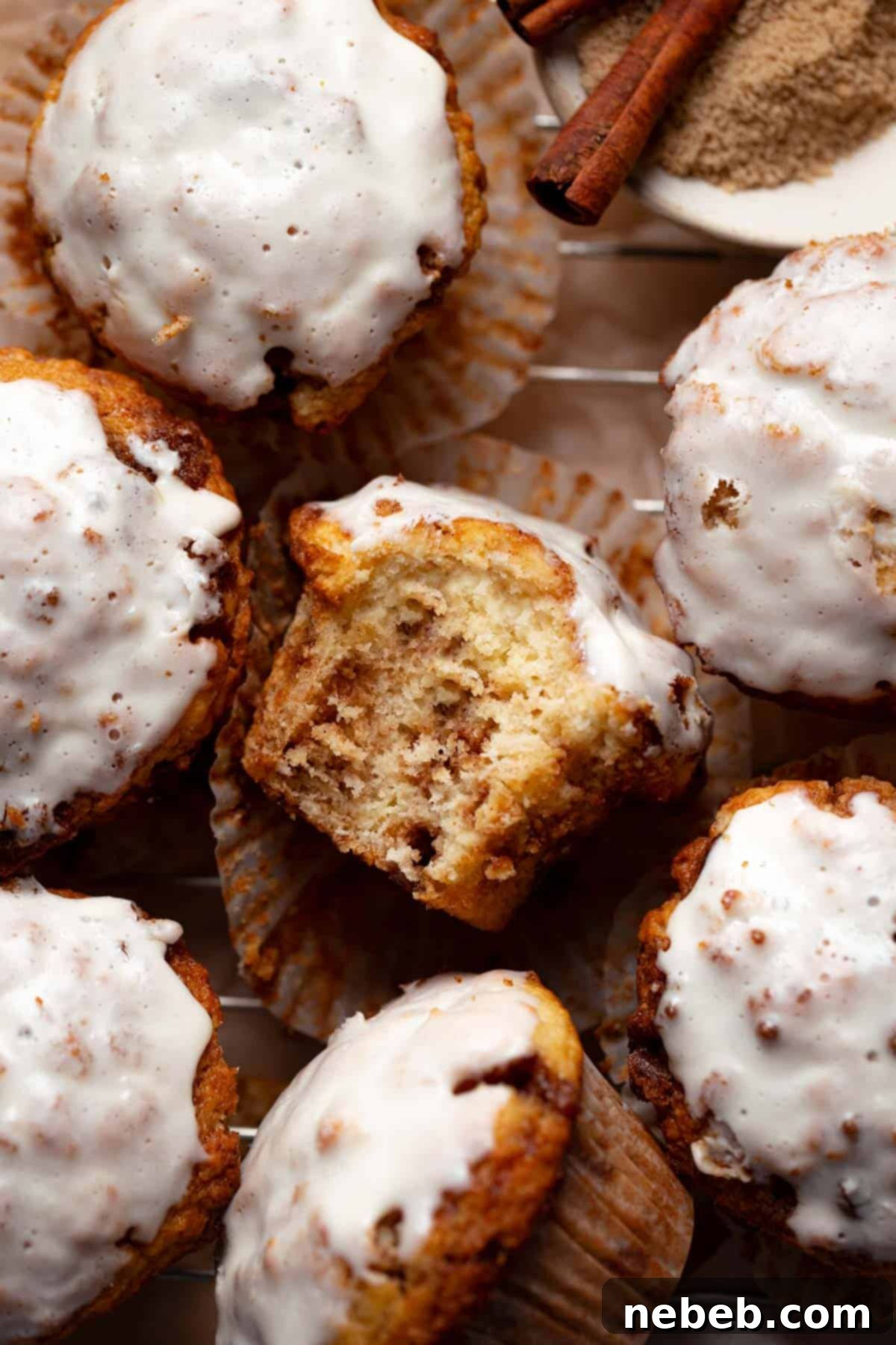 A cinnamon roll muffin with a bite taken out of it to show the cinnamon sugar swirls inside.