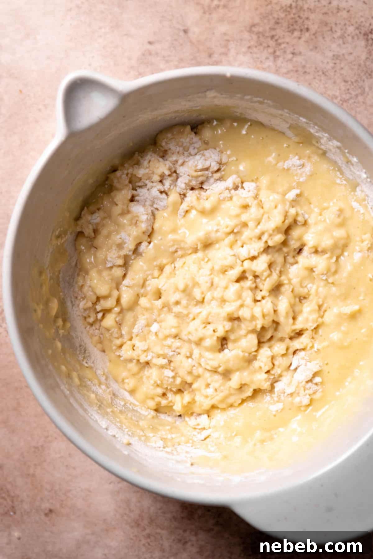 A mixing bowl with the muffin batter ingredients mixed together with some dry flour remaining.