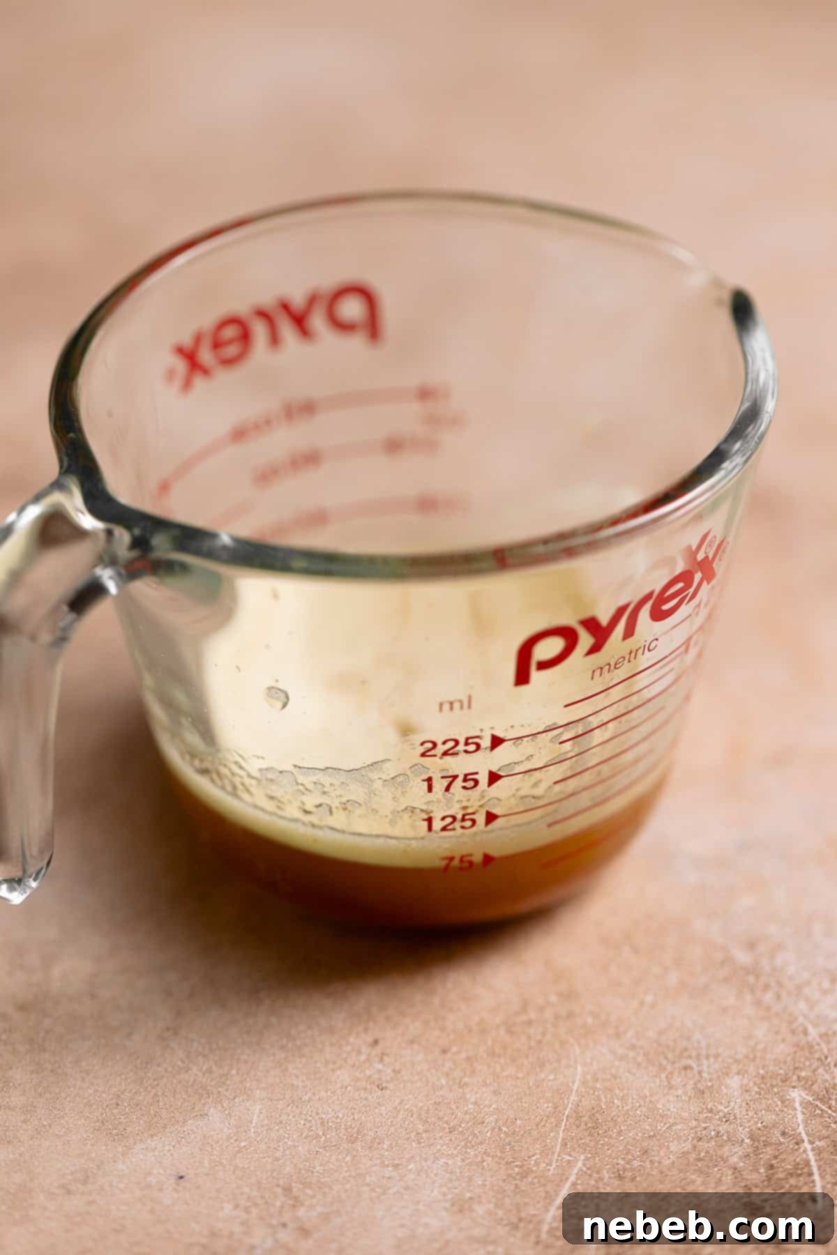 Brown butter cooling in a glass pyrex measuring cup, showing its golden-amber color and nutty brown solids.