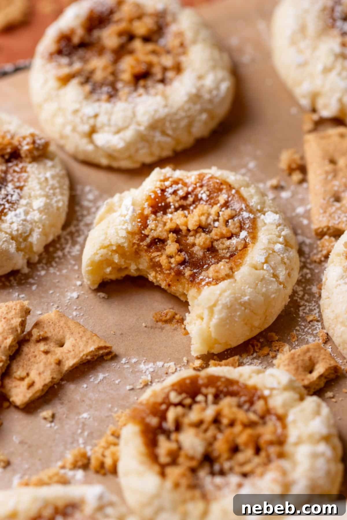 A half-eaten pumpkin cream cheese cookie revealing its creamy pumpkin cheesecake filling and graham cracker topping.