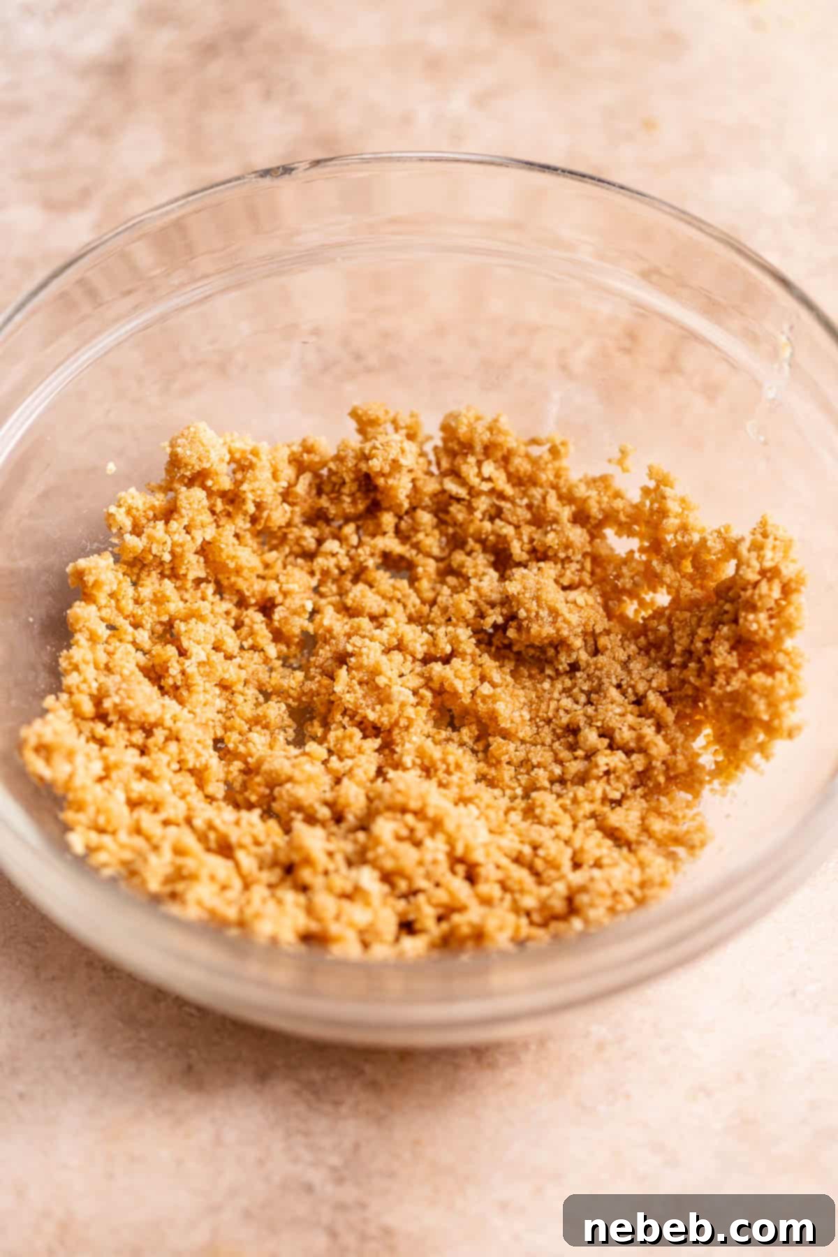 A glass bowl filled with golden brown graham cracker crumbs.