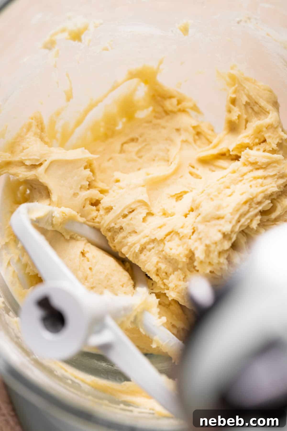 A glass mixing bowl with sticky cream cheese cookie dough, ready for the next step.