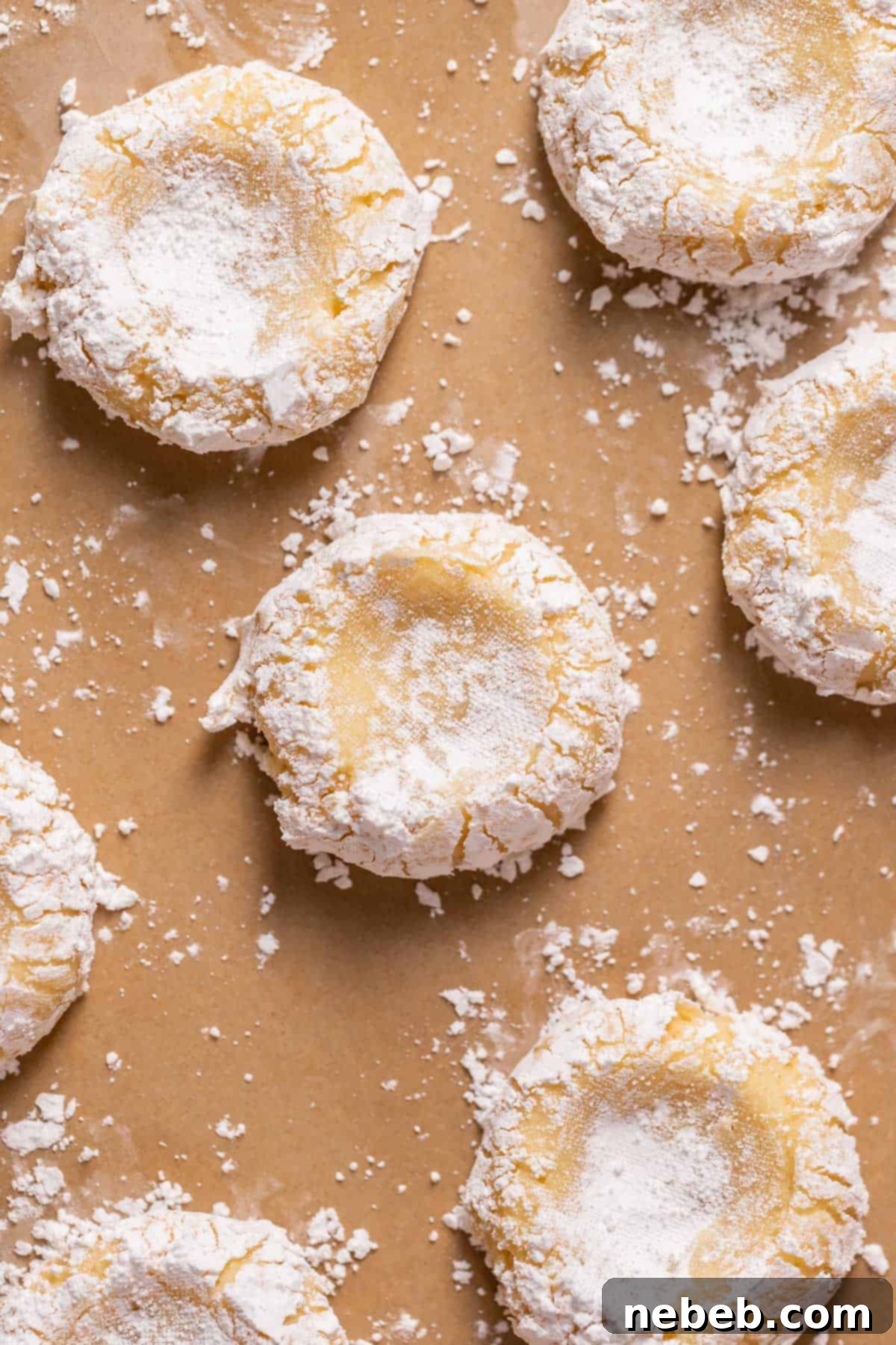 Unbaked cookies with indentations on a baking sheet, ready for the cheesecake filling.