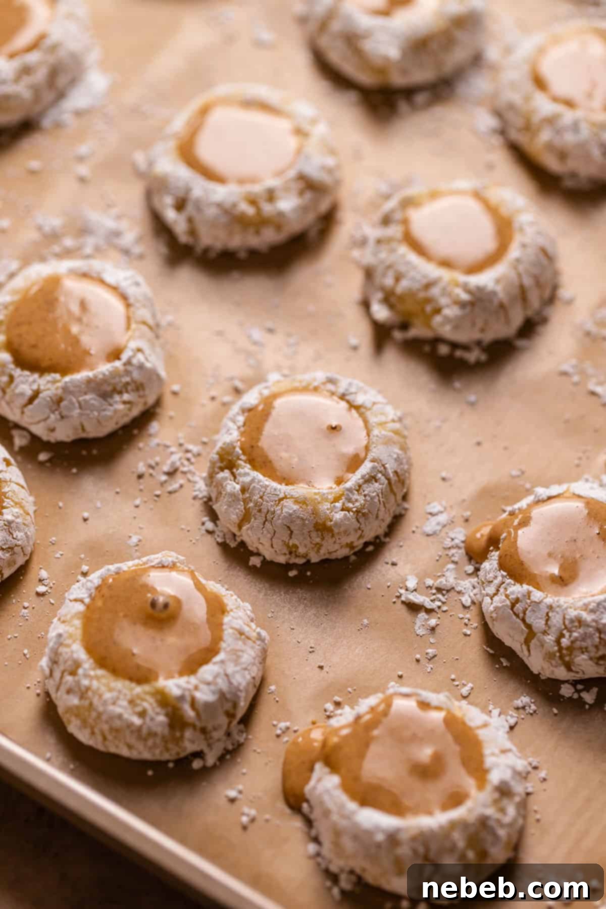 Pumpkin filled cheesecake cookies on a baking sheet, topped with graham cracker crumbs, ready for freezing and baking.
