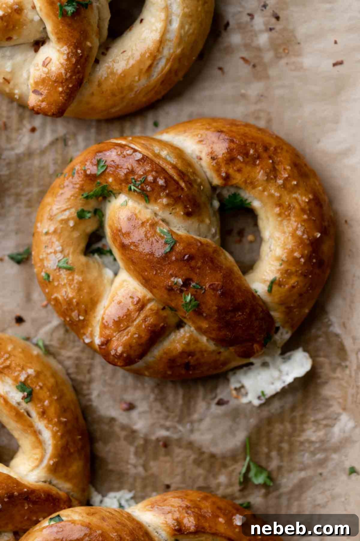 Creamy Spinach Artichoke Stuffed Pretzels 2 stuffed pretzels on a parchment lined baking tray.