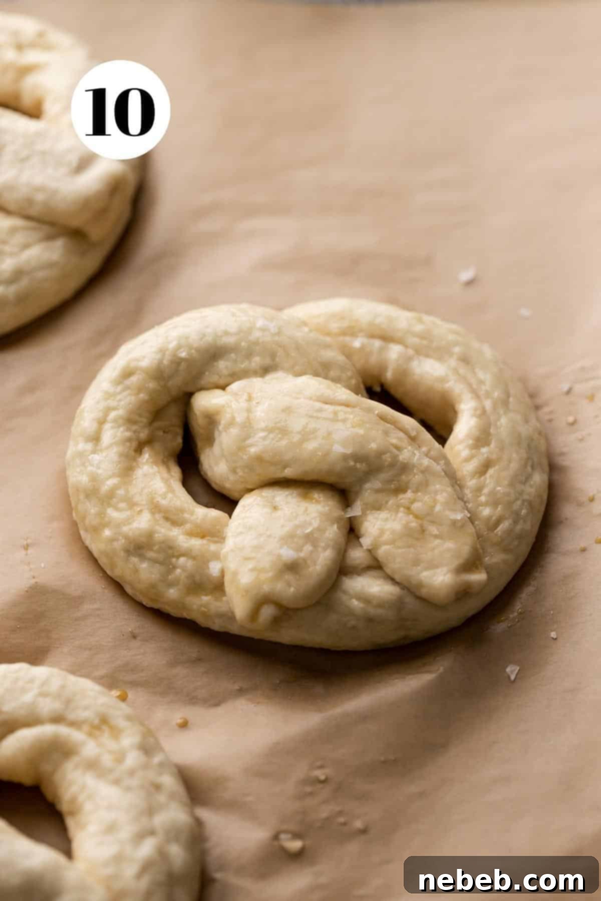 Creamy Spinach Artichoke Stuffed Pretzels 9 a soft pretzel on a parchment lined baking tray before baking.