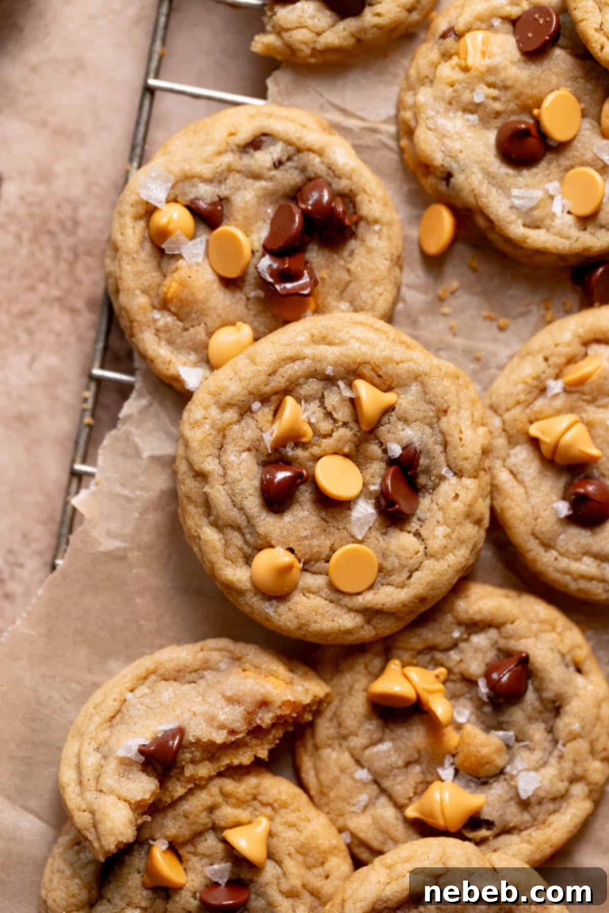 A delectable pile of soft, chewy butterscotch chocolate chip cookies resting on parchment paper, showcasing their golden edges and rich texture.