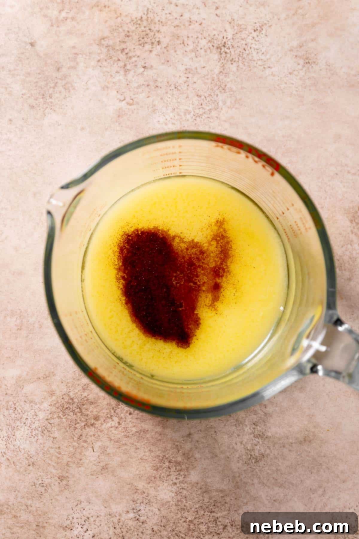 Melted butter with espresso powder stirred in, cooling in a clear glass bowl, ready for the next step of cookie preparation.