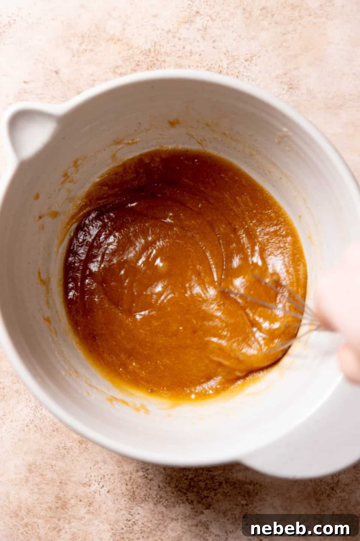 A whole egg, an egg yolk, and vanilla extract being mixed into the butter and sugar mixture in a bowl.