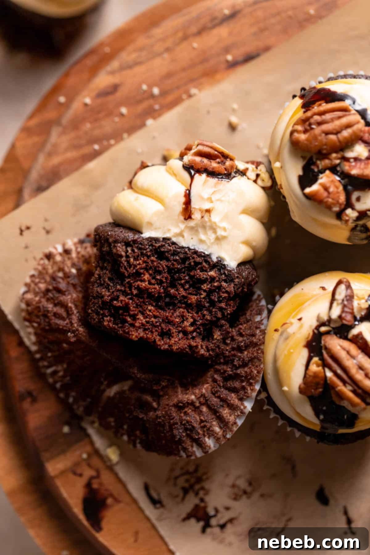 A chocolate cupcake with a bite taken out of it on a wooden serving board.