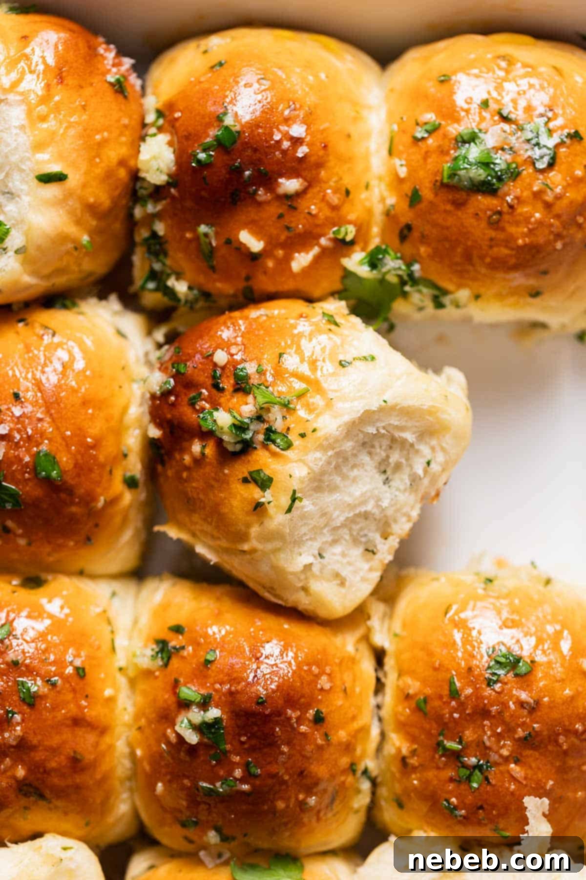 Garlic rolls covered in garlic butter and fresh parsley in a baking pan.